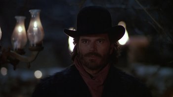 Movie still from “Young Guns” (1988), directed by Christopher Cain – A man wearing a black hat and a black coat; Close Up shot, Low angle