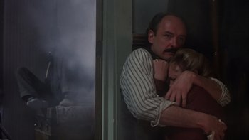 Movie still from “Young Guns” (1988), directed by Christopher Cain – A man and a woman hugging in front of a window; Medium shot, Low angle