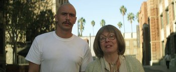 Movie still from “Zeroville” (2019), directed by James Franco – A man and a woman standing next to each other in front of palm trees; Close Up shot, Low angle