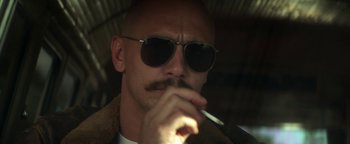 Movie still from “Zeroville” (2019), directed by James Franco – A man with sunglasses and a mustache smoking a cigarette; Close Up shot, Low angle