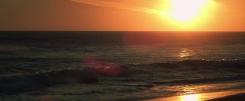 Movie still from “Zeroville” (2019), directed by James Franco – The sun is setting over the ocean with waves in the foreground; Extreme Wide shot, Low angle