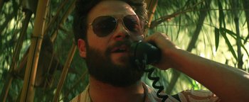 Movie still from “Zeroville” (2019), directed by James Franco – A man talking on a phone while standing under a palm tree; Close Up shot, High angle