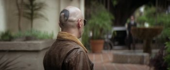 Movie still from “Zeroville” (2019), directed by James Franco – A man with a bald head and a tattoo on his head; Close Up shot, Over the shoulder angle