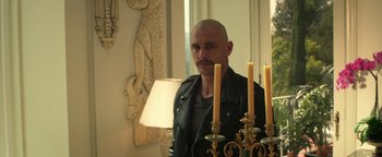 Movie still from “Zeroville” (2019), directed by James Franco – A man with a bald head is standing in front of some candles; Medium shot, Low angle