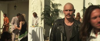 Movie still from “Zeroville” (2019), directed by James Franco – A man in a leather jacket standing in front of a table; Close Up shot, Over the shoulder angle
