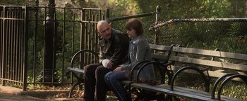 Movie still from “Zeroville” (2019), directed by James Franco – A man sitting on a bench next to a young girl; Medium shot, Over the shoulder angle