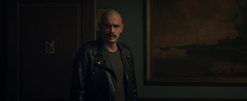Movie still from “Zeroville” (2019), directed by James Franco – A man in a leather jacket standing in front of a painting; Medium shot, Over the shoulder angle