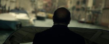 Movie still from “Zeroville” (2019), directed by James Franco – A man wearing a suit and tie looking out a window; Close Up shot, Over the shoulder angle