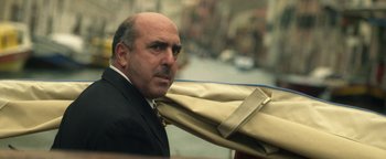 Movie still from “Zeroville” (2019), directed by James Franco – A man in a suit and tie holding a bunch of clothes; Close Up shot, Low angle