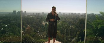 Movie still from “Zeroville” (2019), directed by James Franco – A man standing on top of a building taking a picture with a cell phone; Wide shot, High angle