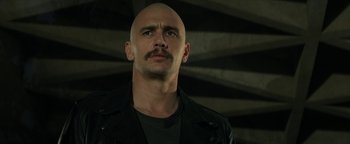 Movie still from “Zeroville” (2019), directed by James Franco – A bald man with a mustache wearing a leather jacket; Close Up shot, Low angle