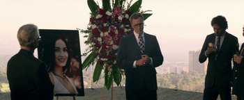 Movie still from “Zeroville” (2019), directed by James Franco – A man standing next to a large flower arrangement; Medium shot, Over the shoulder angle