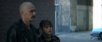 Movie still from “Zeroville” (2019), directed by James Franco – A man standing next to a woman in front of a brick wall; Close Up shot, Over the shoulder angle