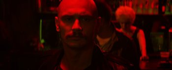 Movie still from “Zeroville” (2019), directed by James Franco – A man with a beard and a mustache is lit up by a red light; Close Up shot, Over the shoulder angle