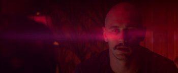 Movie still from “Zeroville” (2019), directed by James Franco – A man with a beard is looking at the camera with a red light coming out of his head; Close Up shot, Over the shoulder angle