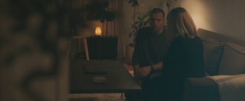 Movie still from “Zoe” (2018), directed by Drake Doremus – A man and a woman sitting at a wooden table; Medium shot, Over the shoulder angle