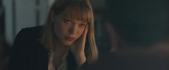 Movie still from “Zoe” (2018), directed by Drake Doremus – A beautiful young woman with blond hair and bangs looking at the camera; Close Up shot, Over the shoulder angle