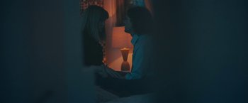 Movie still from “Zoe” (2018), directed by Drake Doremus – Two people are talking in a room with a lamp in the background; Medium shot, Over the shoulder angle