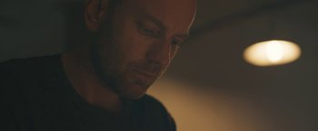 Movie still from “Zoe” (2018), directed by Drake Doremus – A man's face in a dark room; Close Up shot, Low angle