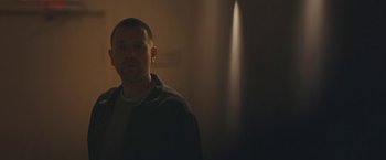 Movie still from “Zoe” (2018), directed by Drake Doremus – A man standing in a room with a blurry background; Medium shot, Low angle