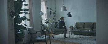 Movie still from “Zoe” (2018), directed by Drake Doremus – A woman is sitting in a chair in a living room; Wide shot, High angle