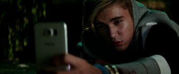 Movie still from “Zoolander 2” (2016), directed by Ben Stiller – A person taking a picture with a cell phone; Close Up shot, Over the shoulder angle