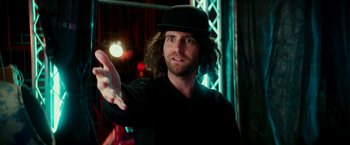 Movie still from “Zoolander 2” (2016), directed by Ben Stiller – A man with long hair wearing a black hat; Medium shot, Low angle