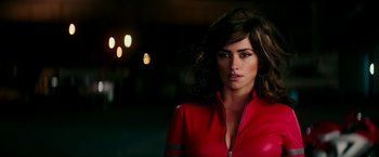 A woman in a red jacket standing next to a building