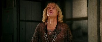 Movie still from “Zoolander 2” (2016), directed by Ben Stiller – A man with long blonde hair wearing a black shirt; Close Up shot, Low angle