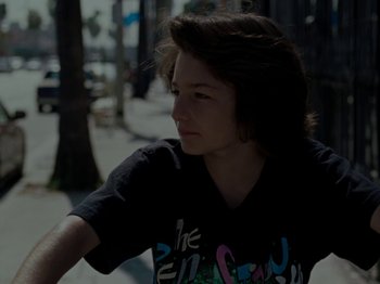 Movie still from “Mid90s” (2018), directed by Jonah Hill – A young person sitting on the ground in the street; Close Up shot, Low angle
