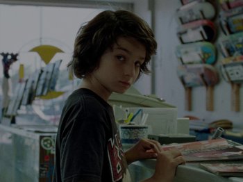 Movie still from “Mid90s” (2018), directed by Jonah Hill – A young boy is looking at a book; Close Up shot, Over the shoulder angle