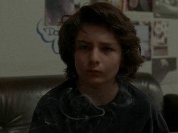 Movie still from “Mid90s” (2018), directed by Jonah Hill – A young boy is smoking a cigarette while sitting on a couch; Close Up shot, Over the shoulder angle
