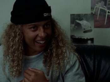 Movie still from “Mid90s” (2018), directed by Jonah Hill – A person with curly blonde hair wearing a black hat; Close Up shot, High angle