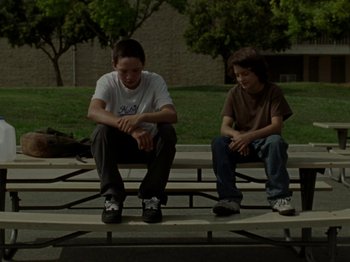 Movie still from “Mid90s” (2018), directed by Jonah Hill – Two young men sitting on a bench in a park; Wide shot, Low angle