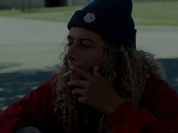 Movie still from “Mid90s” (2018), directed by Jonah Hill – A person that is sitting down smoking a cigarette; Close Up shot, Low angle