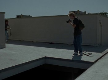 Movie still from “Mid90s” (2018), directed by Jonah Hill – A man standing on a skateboard in front of an empty pool; Wide shot, Low angle