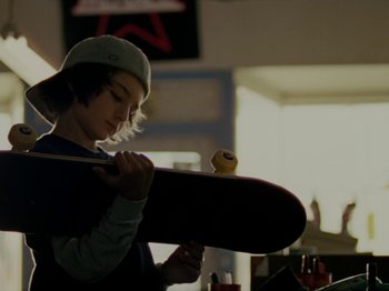 Movie still from “Mid90s” (2018), directed by Jonah Hill – A young boy holding a skateboard in a room; Close Up shot, Low angle