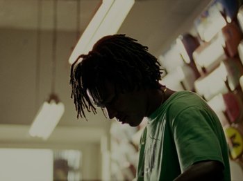 Movie still from “Mid90s” (2018), directed by Jonah Hill – A man with dreads is standing in a room; Close Up shot, Low angle