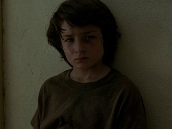 Movie still from “Mid90s” (2018), directed by Jonah Hill – A young boy standing against a wall looking sad; Close Up shot, Low angle