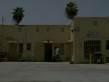 Movie still from “Mid90s” (2018), directed by Jonah Hill – A man walking down the street in front of a building; Extreme Wide shot, Low angle