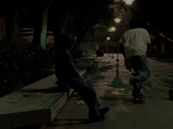 Movie still from “Mid90s” (2018), directed by Jonah Hill – Two skateboarders are sitting on a bench at night; Wide shot, High angle