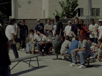 Movie still from “Mid90s” (2018), directed by Jonah Hill – A group of skateboarders gathered around a bench; Wide shot, High angle