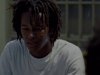 Movie still from “Mid90s” (2018), directed by Jonah Hill – A man with dreadlocks sitting in front of a window; Close Up shot, Low angle