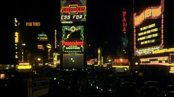 Movie still from “Bullets Over Broadway” (1994), directed by Woody Allen – A view of a busy city at night with neon lights; Extreme Wide shot, High angle