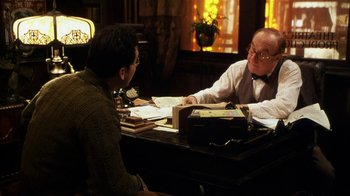 Movie still from “Bullets Over Broadway” (1994), directed by Woody Allen – Two men sitting at a table talking to each other; Medium shot, Over the shoulder angle