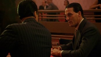 Movie still from “Bullets Over Broadway” (1994), directed by Woody Allen – A man in a suit and tie sitting next to another man in a suit and tie; Medium shot, Over the shoulder angle