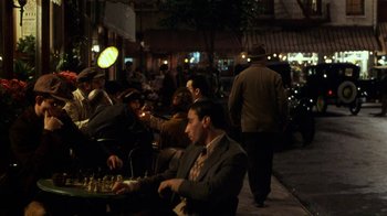 Movie still from “Bullets Over Broadway” (1994), directed by Woody Allen – A group of people sitting at a table playing chess; Wide shot, High angle