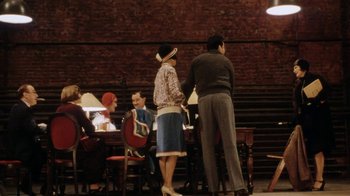 Movie still from “Bullets Over Broadway” (1994), directed by Woody Allen – A group of people sitting at a table in front of a brick wall; Wide shot, High angle