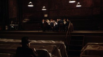 Movie still from “Bullets Over Broadway” (1994), directed by Woody Allen – A group of people sitting at a table in a theater; Extreme Wide shot, High angle