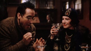 Movie still from “Bullets Over Broadway” (1994), directed by Woody Allen – A man and a woman sitting next to each other holding drinks; Close Up shot, Over the shoulder angle
